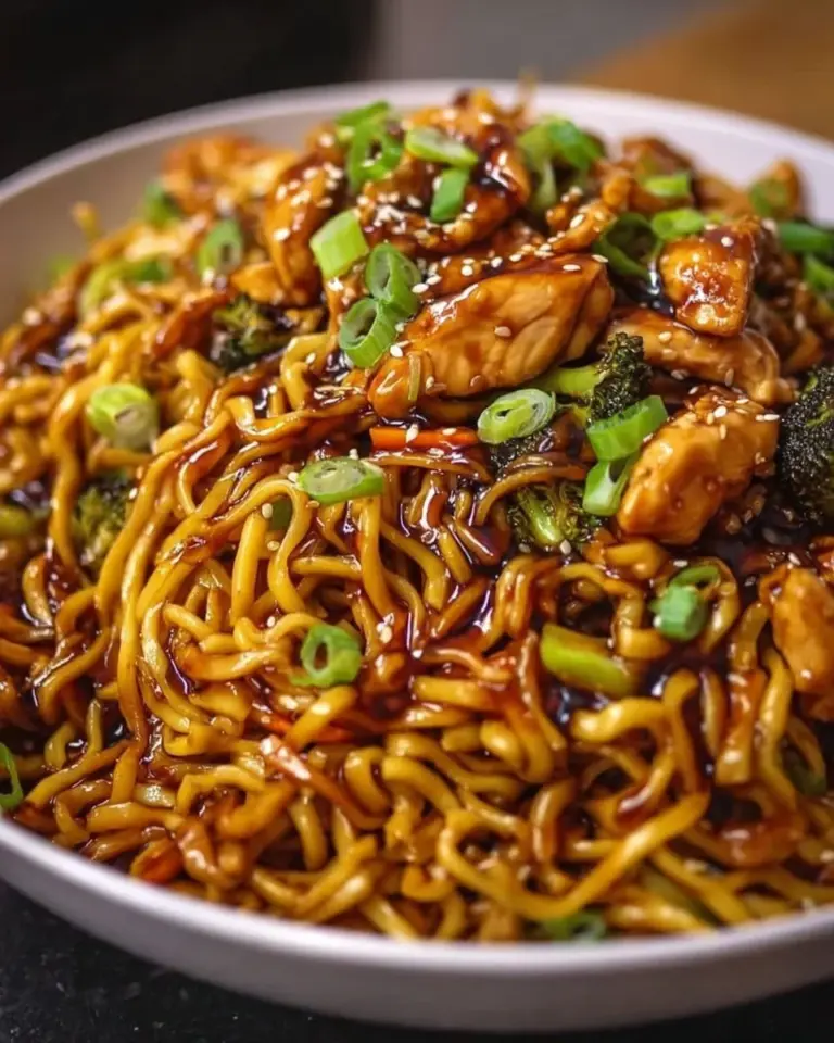 Plate of Sticky Garlic Chicken Noodles garnished with fresh herbs