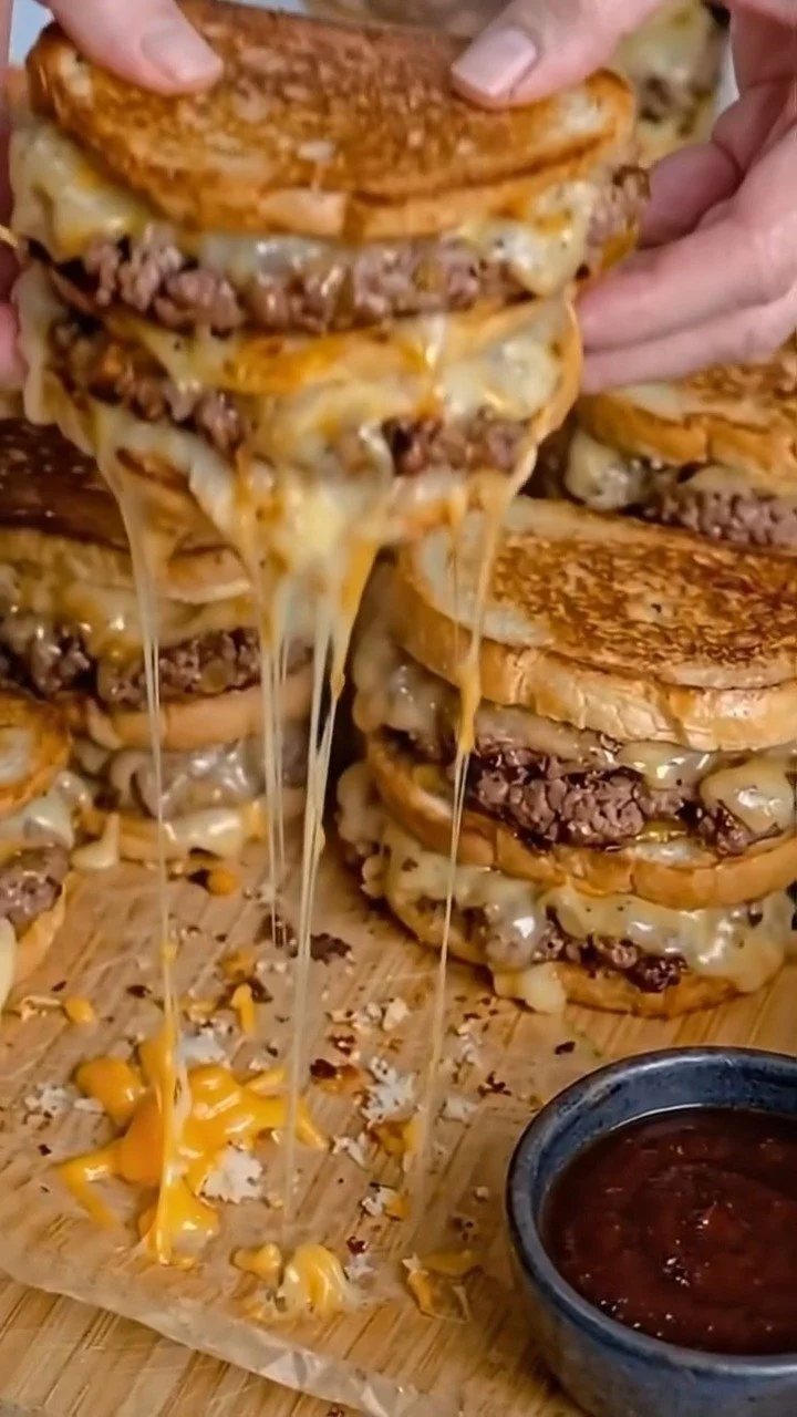 Cheesy patty melt sliders served on a platter with grilled onions.
