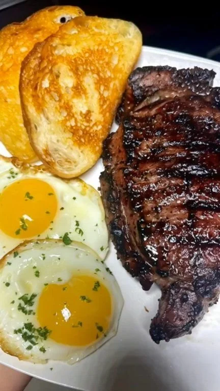 Plate of steak and fried eggs alongside sourdough toast