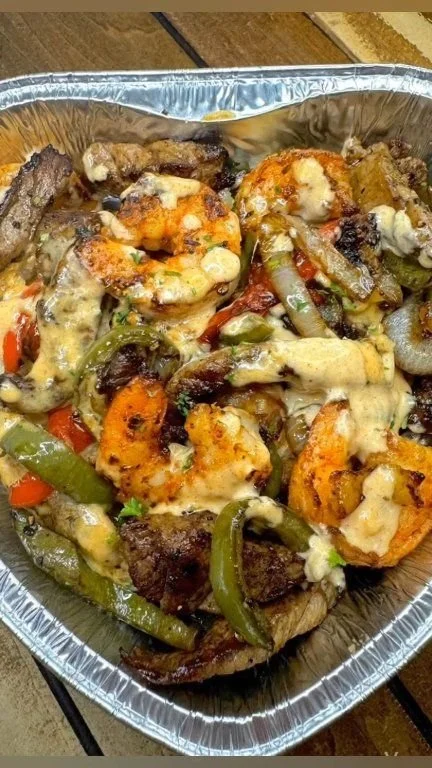 Cheesy steak and shrimp loaded baked potato topped with cheese and herbs